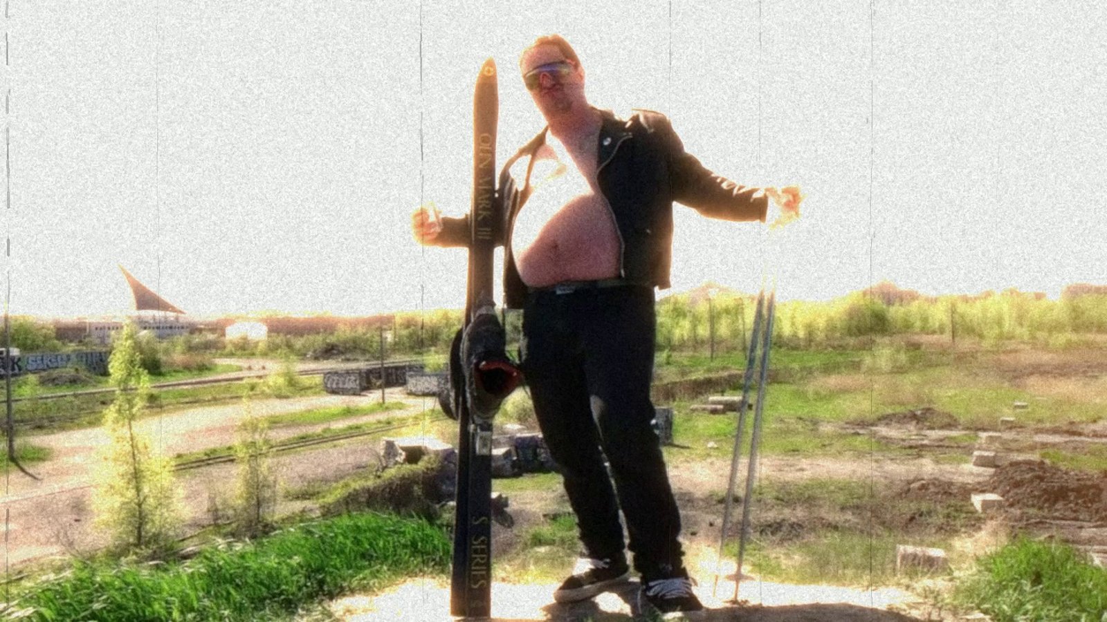 Daylight footage: a skier posing on a dirt lot with a stadium behind. After Super8 Film Lab, full apocalypse look: everything on, with a leak and a scratch run.
