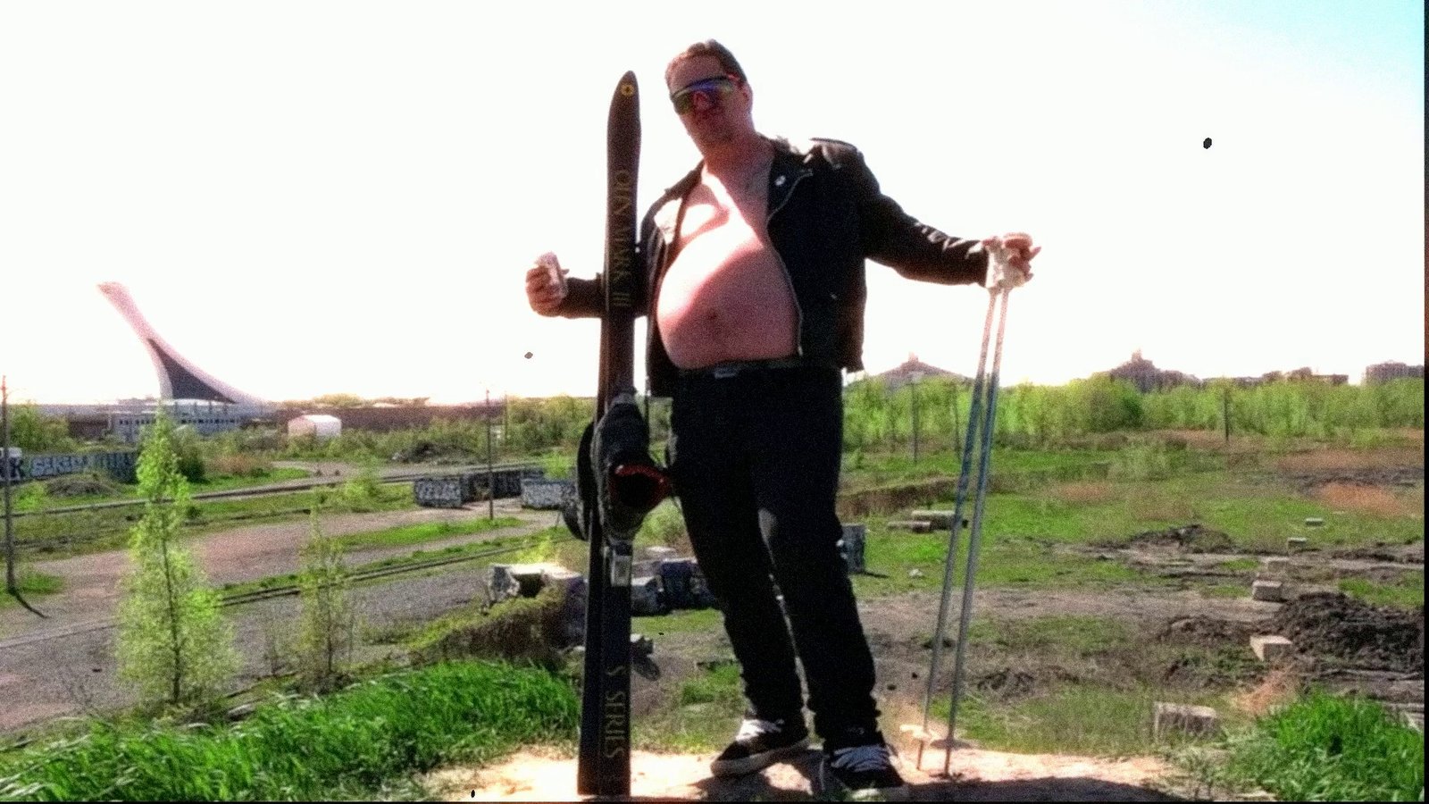 Daylight footage: a skier posing on a dirt lot with a stadium behind. After Super8 Film Lab, grindhouse (v1 engine) look: the original V1 grindhouse engine.